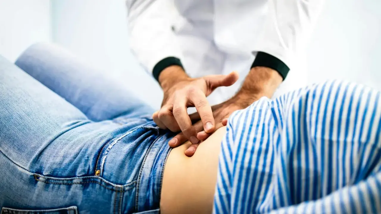 Läkare undersöker en patient med ont i nedre delen av magen.