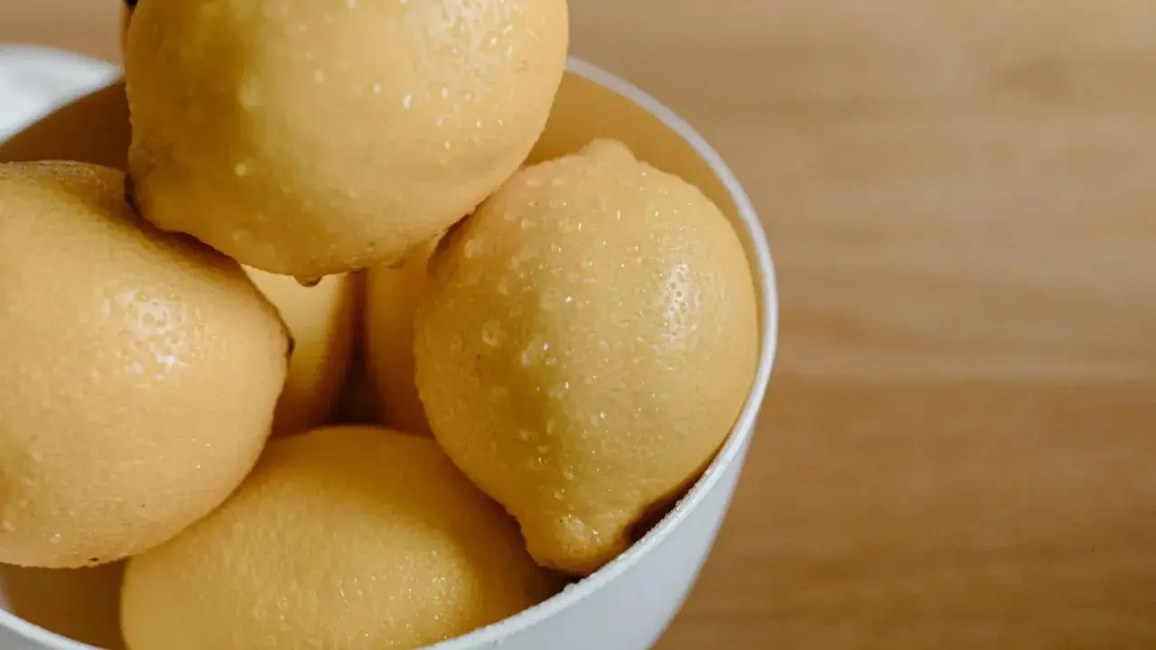En skål med saftiga, vattendroppande citroner. Citronsyran i dem är en hemlighet för strålande hudvård.