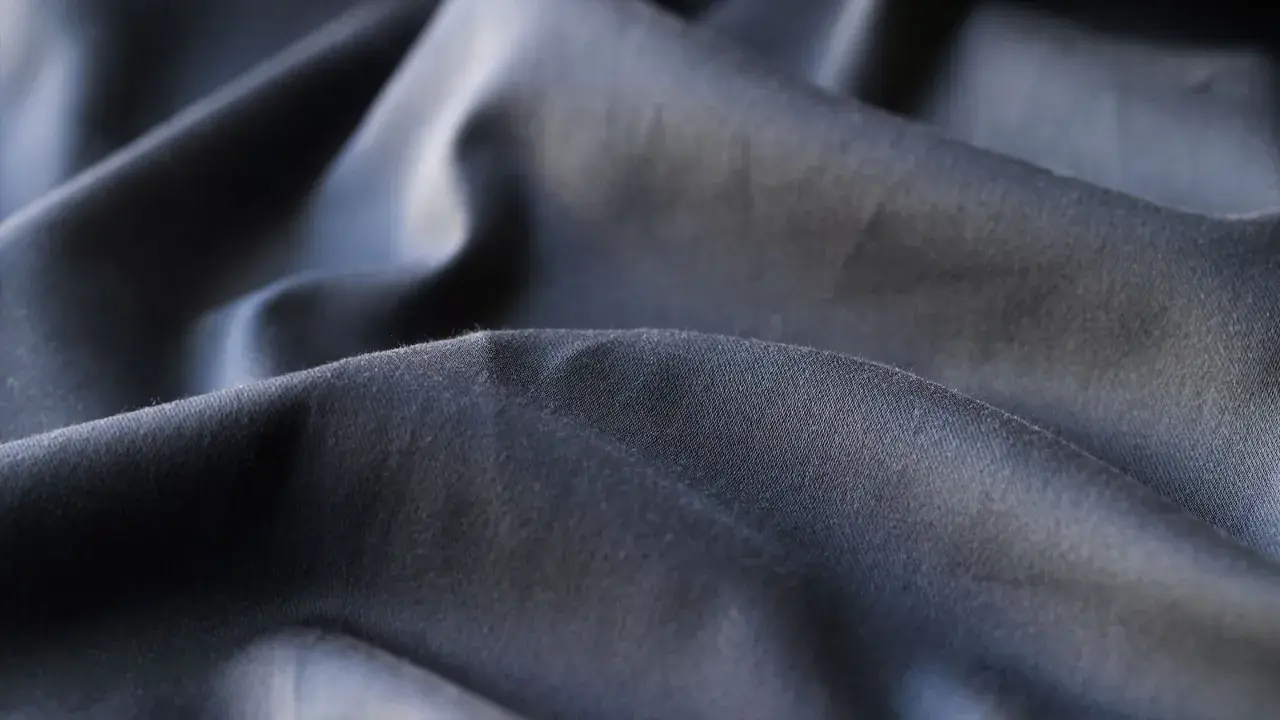 Mörkt, skrynkligt tyg i polyester. En av polyester nackdelar är att det lätt skrynklar sig och kan kännas syntetiskt.
