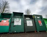 Gröna insamlingscontainrar för kläder, textil och skor. En del av dem visar vad som menas med återvinning genom att samla in begagnade kläder.