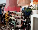 En inlämning second hand-butik med kläder på galgar, skor på hyllor och en skyltdocka i klänning.