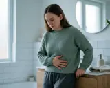 Kvinna med handen på magen, känner obehag som kan kopplas till mykoplasma i underlivet.