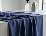 Mörkblå viskos draperad över en betongyta, med en sprayflaska och ett strykjärn i bakgrunden. Perfekt för att stryka viskos.