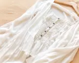 Vit blus i mjukt material rayon, med smockdetaljer och knappar framtill. Lätt och luftig, perfekt för sommaren.