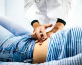 Läkare undersöker en patient med ont i nedre delen av magen.