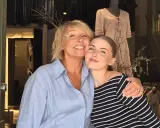 Två glada kvinnor kramas framför en butik som säljer kläder på kommissionsförsäljning.