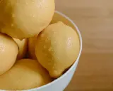 En skål med saftiga, vattendroppande citroner. Citronsyran i dem är en hemlighet för strålande hudvård.