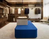 En lyxig walk-in-closet med mörka trädetaljer och en blå sittbänk, allt i en elegant italiensk stil.