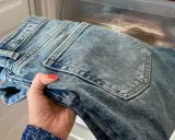 Hand håller nya jeans som luktar illa, placerade i en frys för att fräscha upp dem.