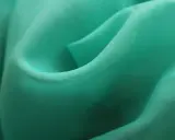 Detaljerad bild av turkos polyestertyg som visar hur tillverkas polyester genom vävning.