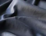 Mörkt, skrynkligt tyg i polyester. En av polyester nackdelar är att det lätt skrynklar sig och kan kännas syntetiskt.