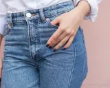 En hand vilar i fickan på ett par ljusblå jeans. Kanske är det en ny trend, jeans i frysen, för att få dem extra krispiga?