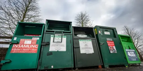 Gröna insamlingscontainrar för kläder, textil och skor. En del av dem visar vad som menas med återvinning genom att samla in begagnade kläder.