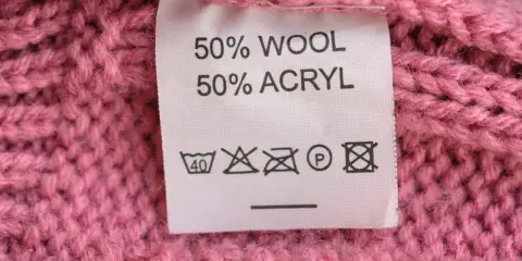 Tvättråd på en rosa stickad tröja: 50% ull, 50% akryl. Kan indikera nackdelar med ull som känslighet för höga temperaturer.