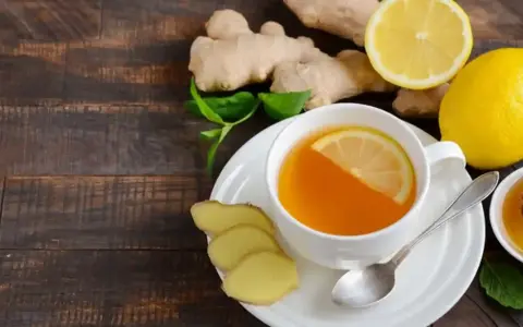 En kopp ingefärste med citron och honung, omgiven av färsk ingefära och citron. Perfekt för en hosta.