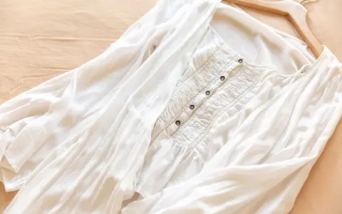 Vit blus i mjukt material rayon, med smockdetaljer och knappar framtill. Lätt och luftig, perfekt för sommaren.