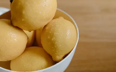 En skål med saftiga, vattendroppande citroner. Citronsyran i dem är en hemlighet för strålande hudvård.