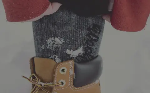Vinterkläder med ett material som andas håller dig varm och torr. Snöflingor på en stickad strumpa och en känga.