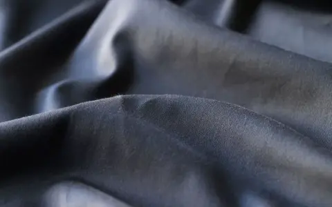 Mörkt, skrynkligt tyg i polyester. En av polyester nackdelar är att det lätt skrynklar sig och kan kännas syntetiskt.