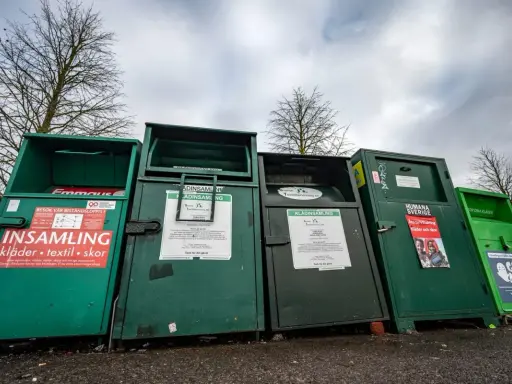 Gröna insamlingscontainrar för kläder, textil och skor. En del av dem visar vad som menas med återvinning genom att samla in begagnade kläder.