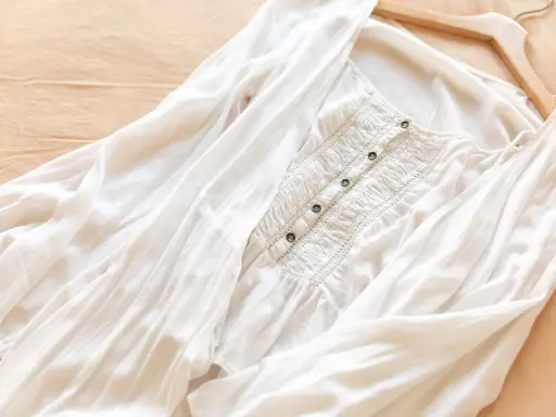 Vit blus i mjukt material rayon, med smockdetaljer och knappar framtill. Lätt och luftig, perfekt för sommaren.