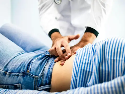 Läkare undersöker en patient med ont i nedre delen av magen.