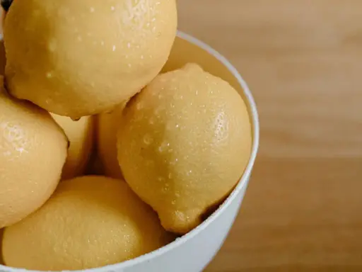 En skål med saftiga, vattendroppande citroner. Citronsyran i dem är en hemlighet för strålande hudvård.