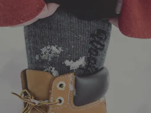 Vinterkläder med ett material som andas håller dig varm och torr. Snöflingor på en stickad strumpa och en känga.