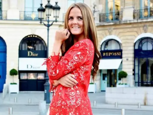 En kvinna i röd spetsklänning poserar framför Dior i Paris. Drömmer om ett jobb inom mode.