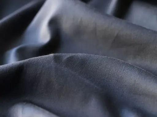 Mörkt, skrynkligt tyg i polyester. En av polyester nackdelar är att det lätt skrynklar sig och kan kännas syntetiskt.