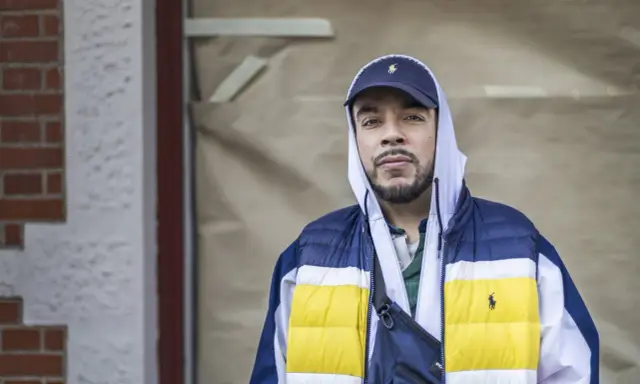 Man i hip hop style med keps och färgglad jacka.