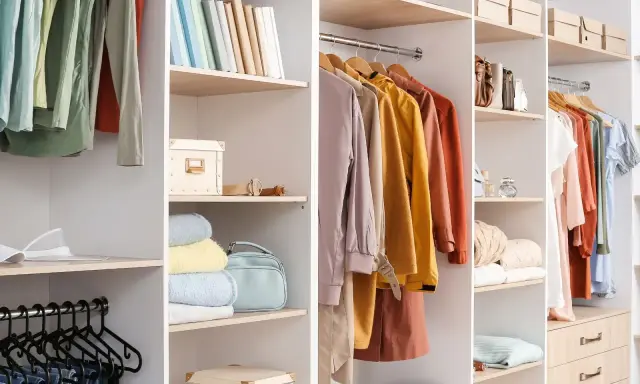 En garderob som behöver rensas. Kläder på galgar, böcker, lådor och accessoarer organiserade på hyllor.
