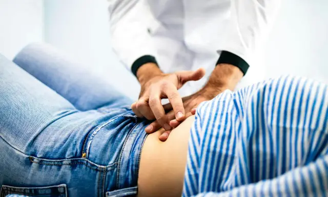 Läkare undersöker en patient med ont i nedre delen av magen.