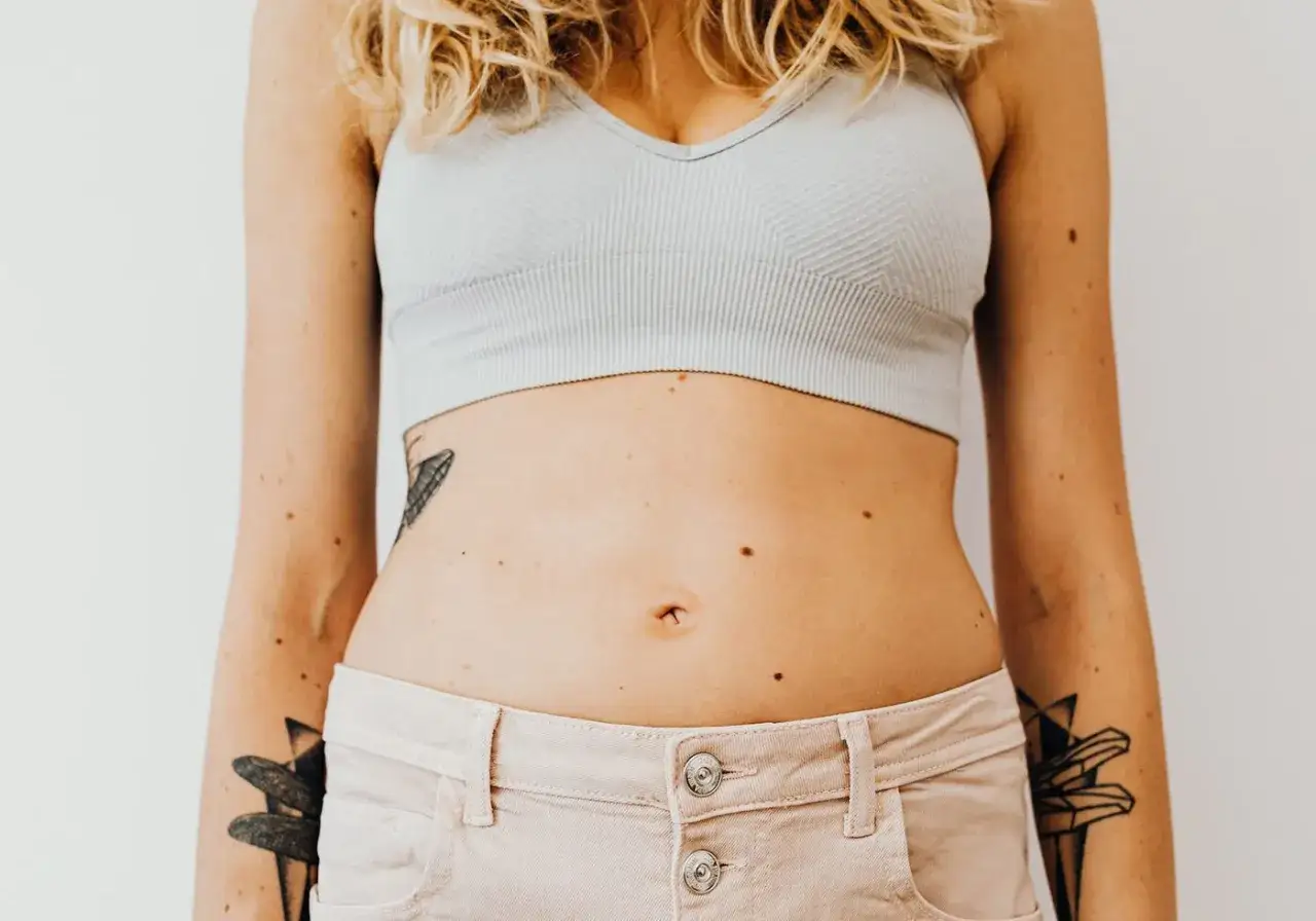 En kvinna med tatueringar p&aring; armarna och magen, som kan vara ett tecken p&aring; glutenintolerans symptom.