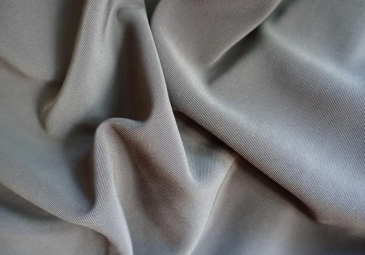 En gr&aring; bomull polyester blandning med en fin textur, draperad i mjuka veck.